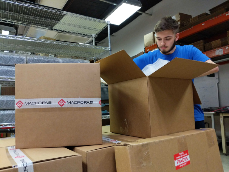 A MacroFab Team Member boxing up shipments.